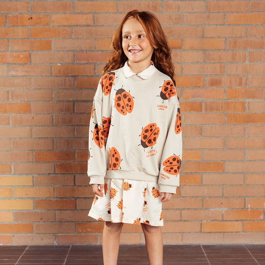 Buzo infantil beige con mariquita Ladybug, estampado total de mariquitas naranjas y la frase “The ladybug concierge”, prenda Unisex y versátil, tela suave y abrigadora para días frescos - LOBSTER mini