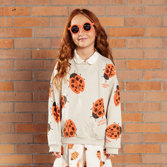 Buzo infantil beige con mariquita Ladybug, estampado total de mariquitas naranjas y la frase “The ladybug concierge”, prenda Unisex y versátil, tela suave y abrigadora para días frescos - LOBSTER mini