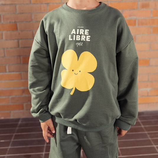 Buzo verde militar estampado trébol amarillo, hecho en tela suave y delicada al tacto, con diseño estampado en el frente y un detalle narrativo en la parte trasera - LOBSTER mini