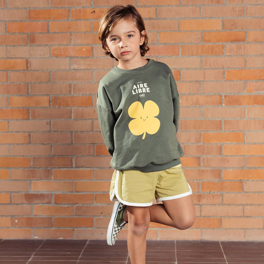 Buzo verde militar estampado trébol amarillo, hecho en tela suave y delicada al tacto, con diseño estampado en el frente y un detalle narrativo en la parte trasera - LOBSTER mini