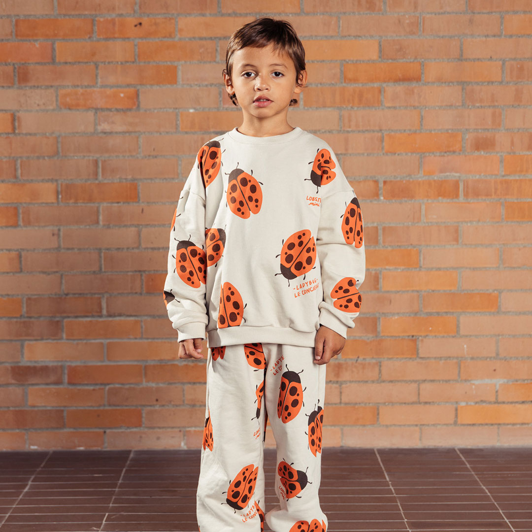 Buzo infantil beige con mariquita Ladybug, estampado total de mariquitas naranjas y la frase “The ladybug concierge”, prenda Unisex y versátil, tela suave y abrigadora para días frescos - LOBSTER mini