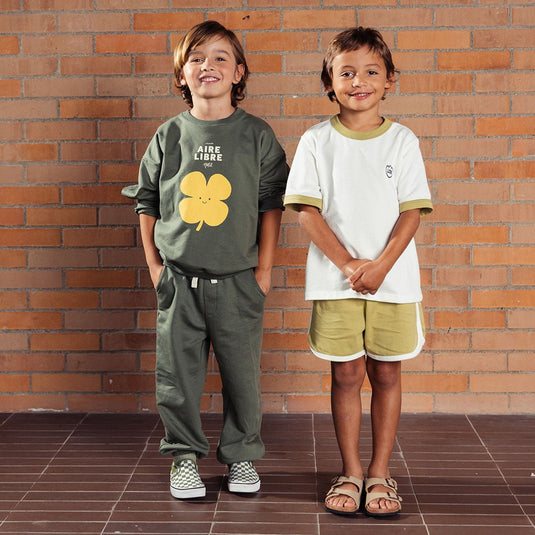 Buzo verde militar estampado trébol amarillo, hecho en tela suave y delicada al tacto, con diseño estampado en el frente y un detalle narrativo en la parte trasera - LOBSTER mini - Cocco Semana 2026
