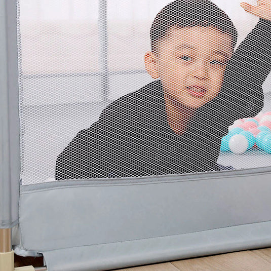 Corral de juego color gris con tapete didáctico de dobleces, hecho en material resistente, con laterales en malla, puerta con cierre para facilitar el ingreso, incluye pelotitas y dos agarraderas